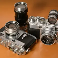 Dwa klasyczne aparaty Nikon z obiektywami, prezentujące różne nikon modele po kolei.