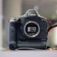 Profesjonalny aparat Canon 1DX Mark III z widocznym mocowaniem obiektywu i paskiem na nadgarstek.