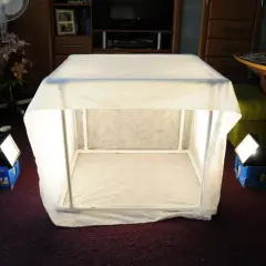 Domowy namiot bezcieniowy DIY, zbudowany z białego materiału i rurek PCV, oświetlony dwoma lampami.