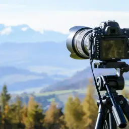 Profesjonalny aparat na statywie gotowy do uchwycenia pięknej **fotografii krajobrazu** z górskim tłem.