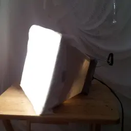 Domowy diy softbox z kartonu i białego materiału, oświetlający scenę.