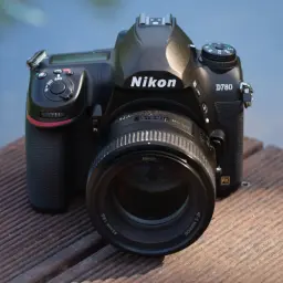 Nikon D780 test. Aparat leży na drewnianym pomoście, obok wody. Obiektyw 85mm f/1.8G.