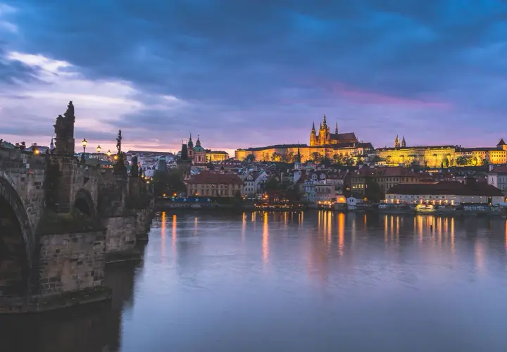 Nastrojowa fotografia nocna Pragi z Mostem Karola i zamkiem na wzgórzu.