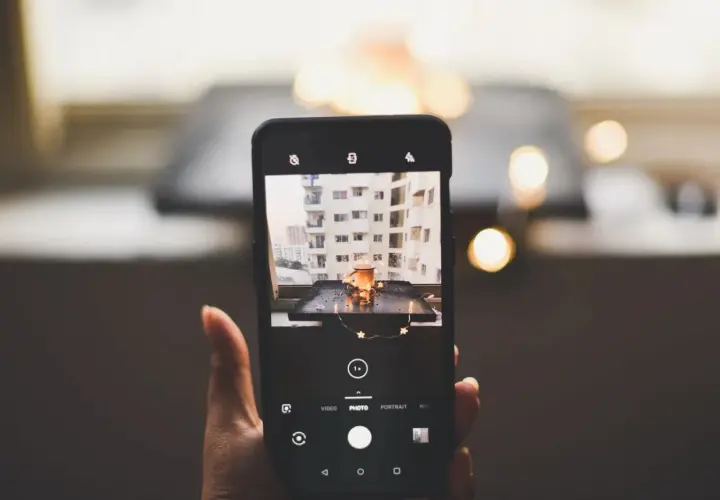 Smartfon robi zdjęcie kubka z napojem i światełek. To przykład fotografii produktowej.