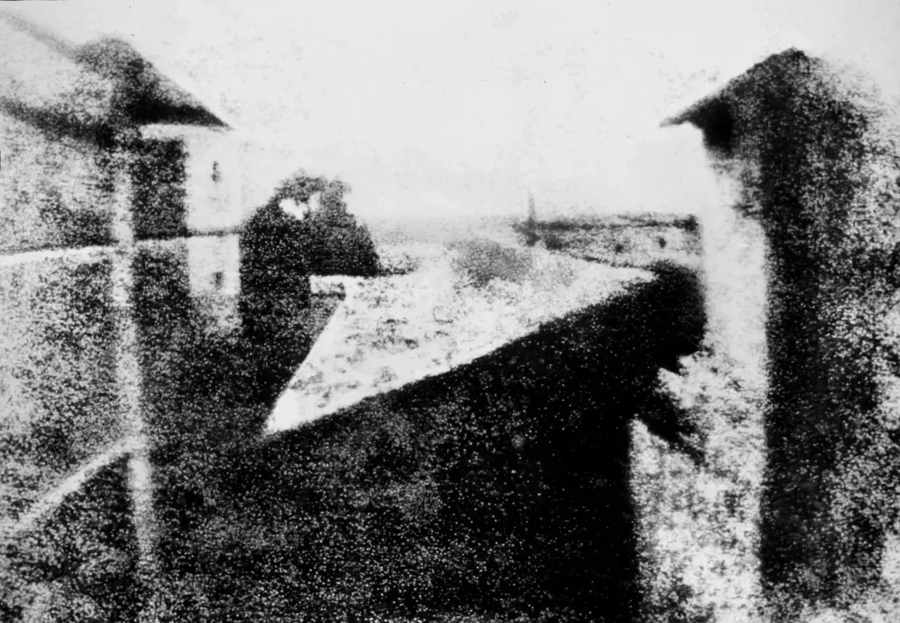 Pierwsza fotografia świata. Widok z okna, budynki, niebo i postać.