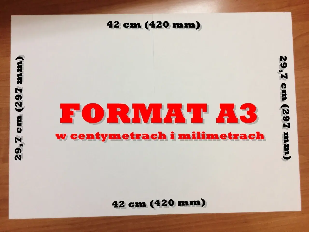 Biała kartka z napisem "FORMAT A3 w centymetrach i milimetrach". Wymiary: 29,7 cm (297 mm) i 42 cm (420 mm). Jaki to format? A3.