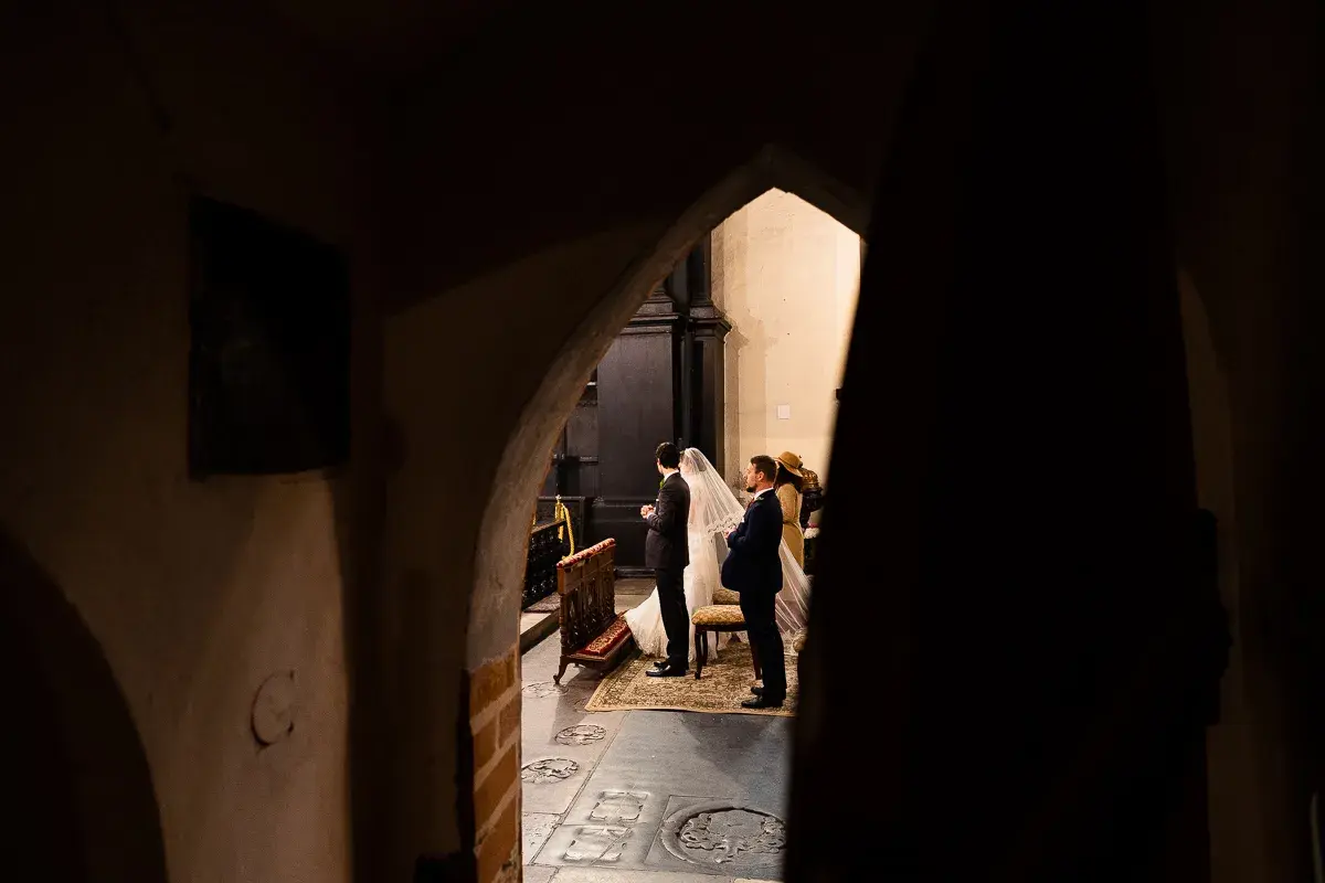 Para dowiedzieć się, jak zostać fotografem ślubnym, warto obserwować takie momenty. Para młoda w kościele, w otoczeniu gości.