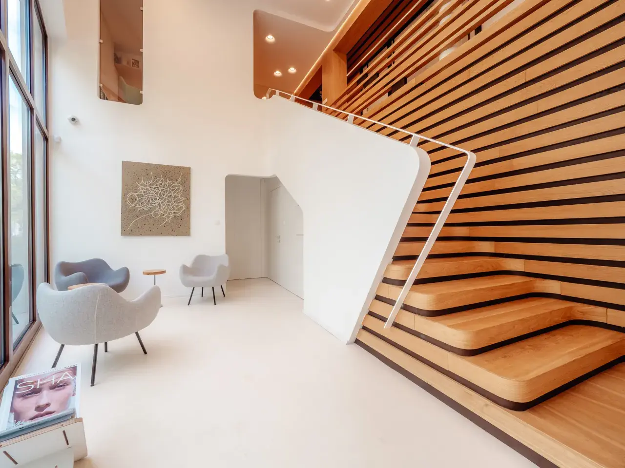 Nowoczesne wnętrze z białymi schodami i drewnianą ścianą. Fotograf architektury uchwycił minimalistyczny design i grę światła.