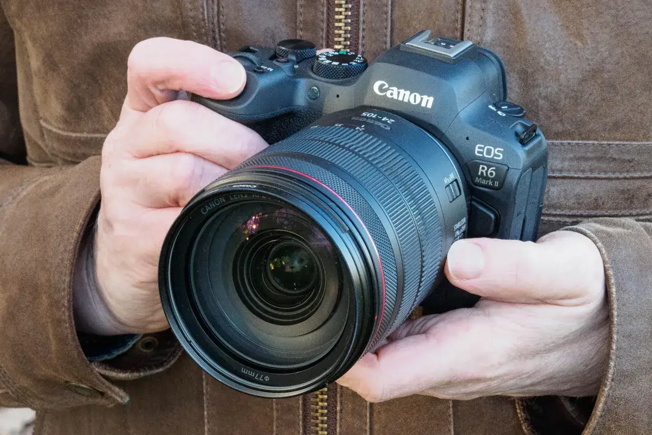 Dłonie trzymają aparat Canon R6 Mark II z obiektywem 24-105mm.
