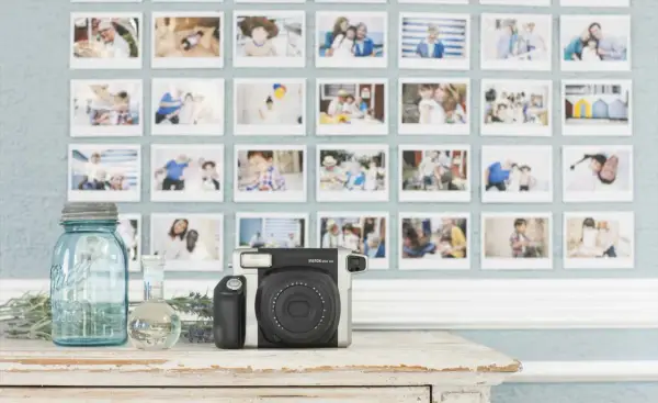 Instax aparat i ściana pełna wspomnień. To idealne miejsce, by zacząć naukę podstaw fotografii i uwieczniać ważne chwile.
